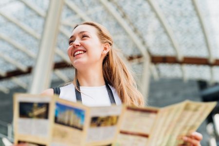 Portrait young caucasian woman traveller holding tourist map smiling discovering and sightseeing